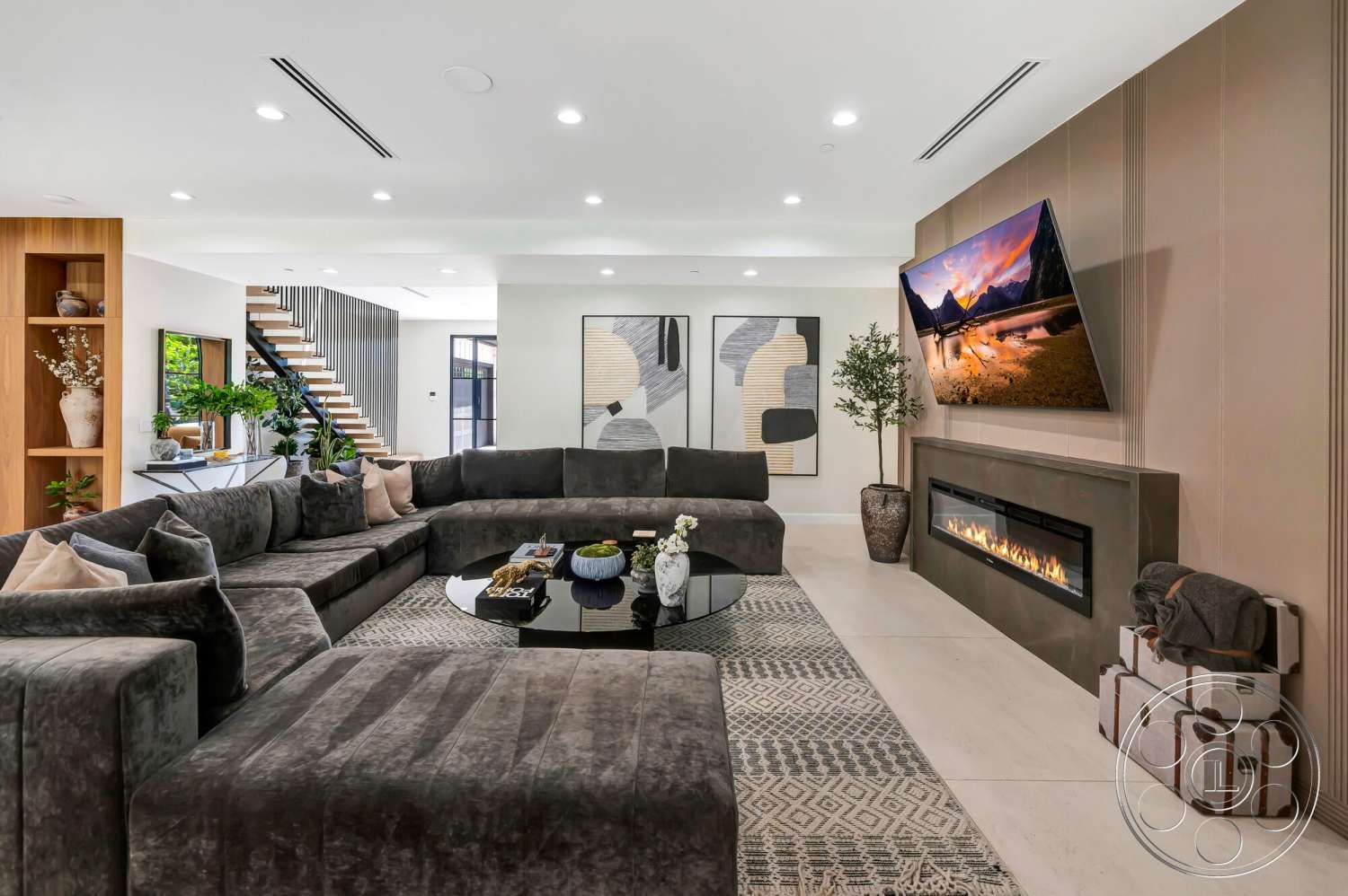 Modern 534 - neutral color palette, glass coffee table, floor-to-ceiling windows, geometric area rug, decorative throw pillows, black abstract wall art, potted indoor plants, built-in wooden shelving, modern living room, fireplace feature wall, textured gray sectional sofa, matte ceramic tile flooring, wood open staircase, linear electric fireplace, dimensional wall paneling