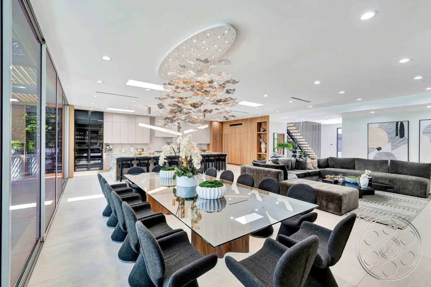 Modern 534 - neutral color palette, natural light, concrete flooring, upholstered dining chairs, glass sliding doors, soft area rug, contemporary art on walls, ceiling light fixture, modern dining table, expansive windows, stainless steel kitchen appliances, open concept living area, decorative indoor plants, L-shaped sectional sofa, floating staircase with wood treads, wood paneling feature wall