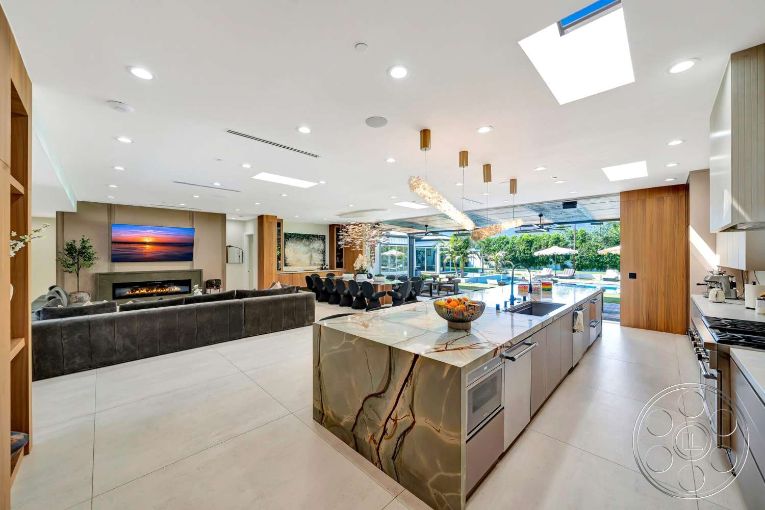 Modern 534 - stone accent wall, modern pendant lighting, floor-to-ceiling windows, dining area with modern chairs, wood accent wall, light wood shelving, open-concept living area, modern sofa design, tile living room flooring, contemporary kitchen cabinets, vaulted ceiling with skylights, built-in fireplace with stone surround, stone kitchen island with veins, glass sliding doors to pool area, large rectangular pool view