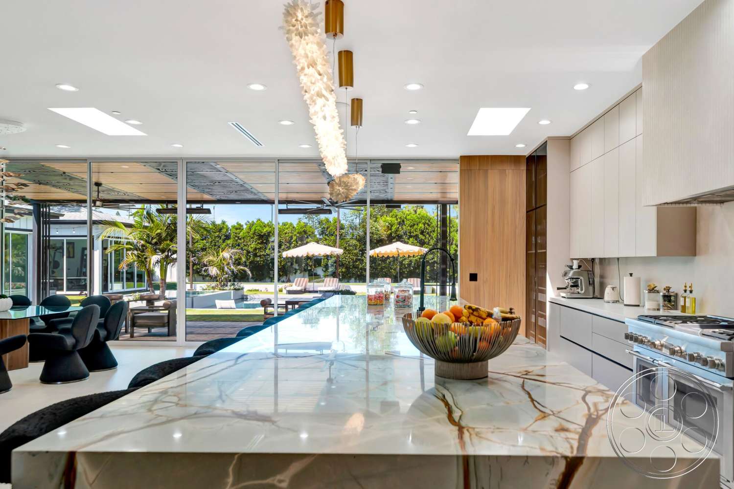 Modern 534 - polished concrete floor, open floor plan, stainless steel appliances, wood cabinetry, modern pendant lighting, glass sliding doors, floor-to-ceiling windows, exposed ceiling, marble kitchen island, natural light through skylights, black upholstered dining chairs, dining area with circular table, view of landscaped backyard