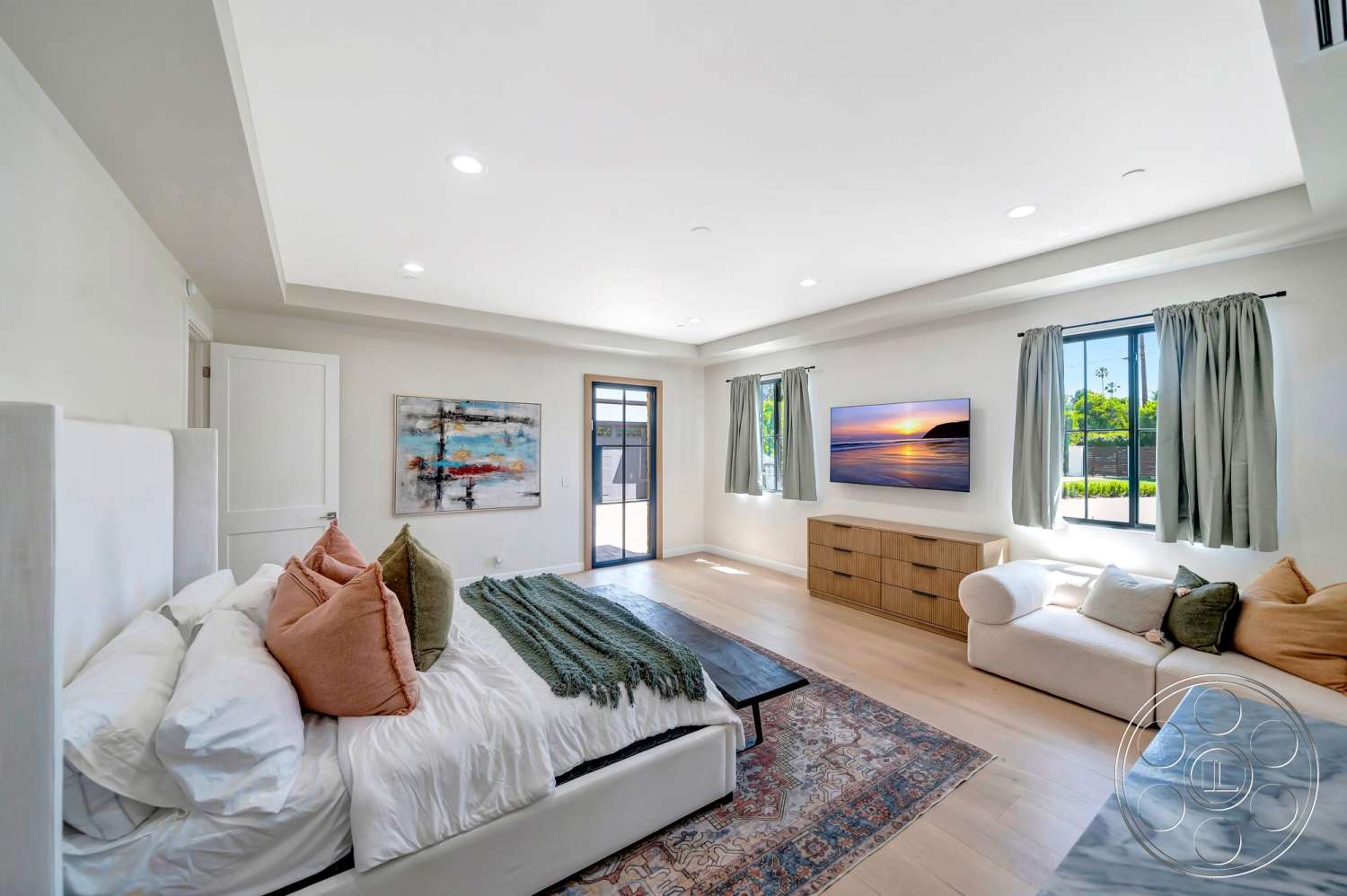 Modern 534 - textured area rug, abstract wall art, vaulted ceiling, decorative throw pillows, flat-screen television, glass window treatments, natural light-filled space, hardwood bedroom floors, white painted walls, built-in wooden dresser, king-sized upholstered bed, light beige sectional sofa, soft linen curtain fabric, green throw blanket