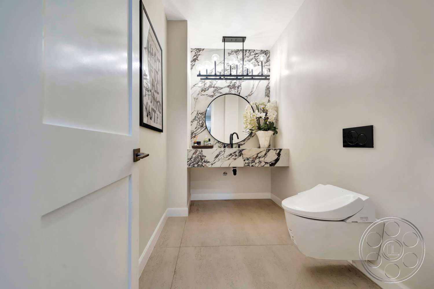 Modern 534 - round mirror, beige tile flooring, minimalist bathroom design, light-colored painted walls, black wall-mounted faucet, marble wall treatment, floating marble sink countertop, black wall-mounted toilet flush plate, light fixture with multiple bulbs