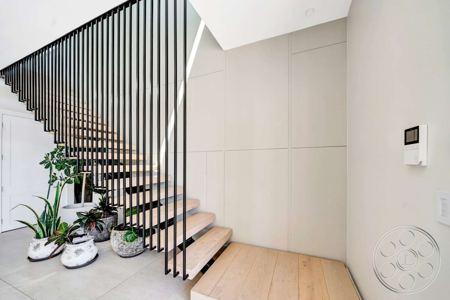 Modern 534 - minimalist design, large potted plants, black metal stair railings, floating stairs, smooth plaster wall, wooden staircase treads, contemporary wall paneling, natural light from staircase