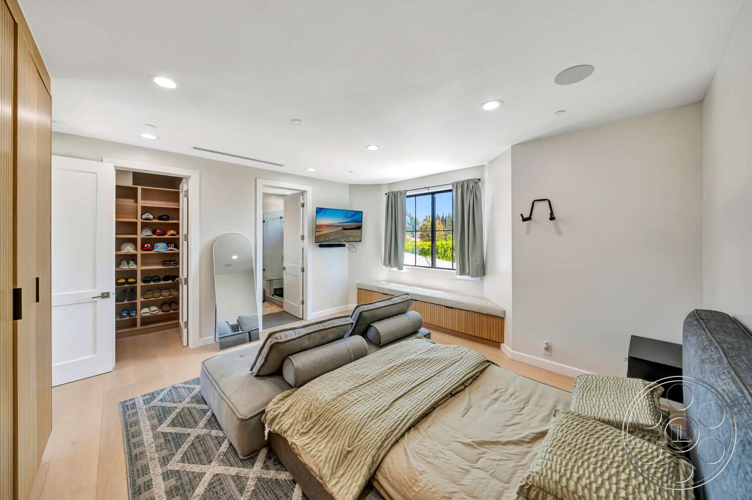 Modern 534 - floor-to-ceiling windows, recessed ceiling lights, hardwood bedroom floors, white painted walls, modern gray upholstered headboard, minimalist sliding closet doors, king-size bed with textured bedding, built-in window seat with wooden paneling, metal sconce wall lighting, decorative area rug with geometric pattern, open closet space with organized shelving