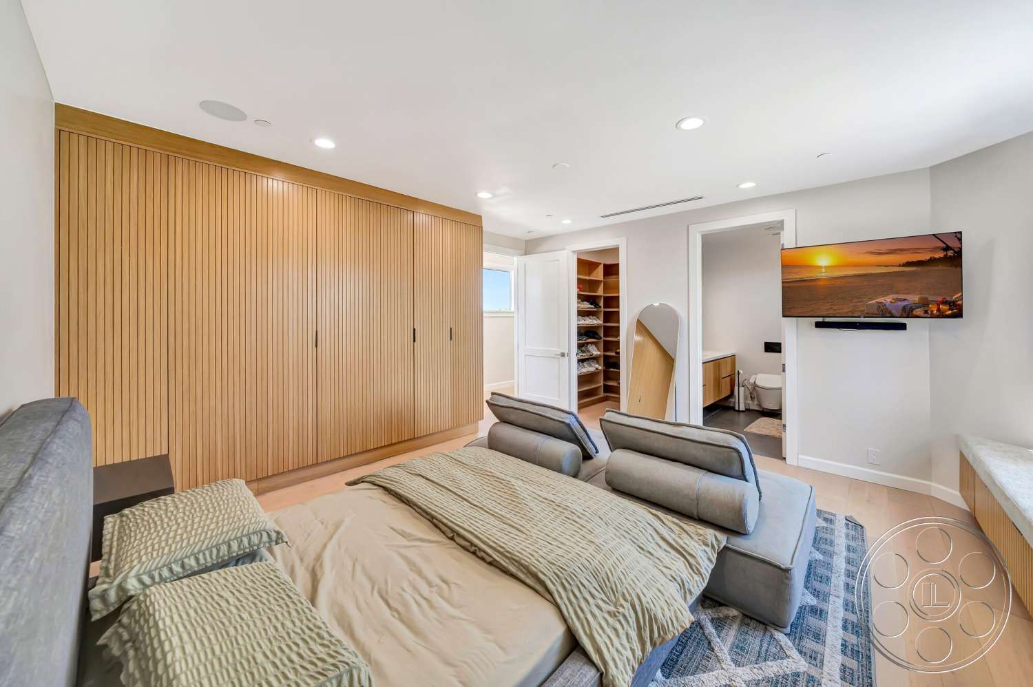 Modern 534 - minimalist design, wall-mounted television, textured bedding, recessed ceiling lights, neutral wall paint, hardwood bedroom floors, soft seating area, open closet space, wood paneling closet doors