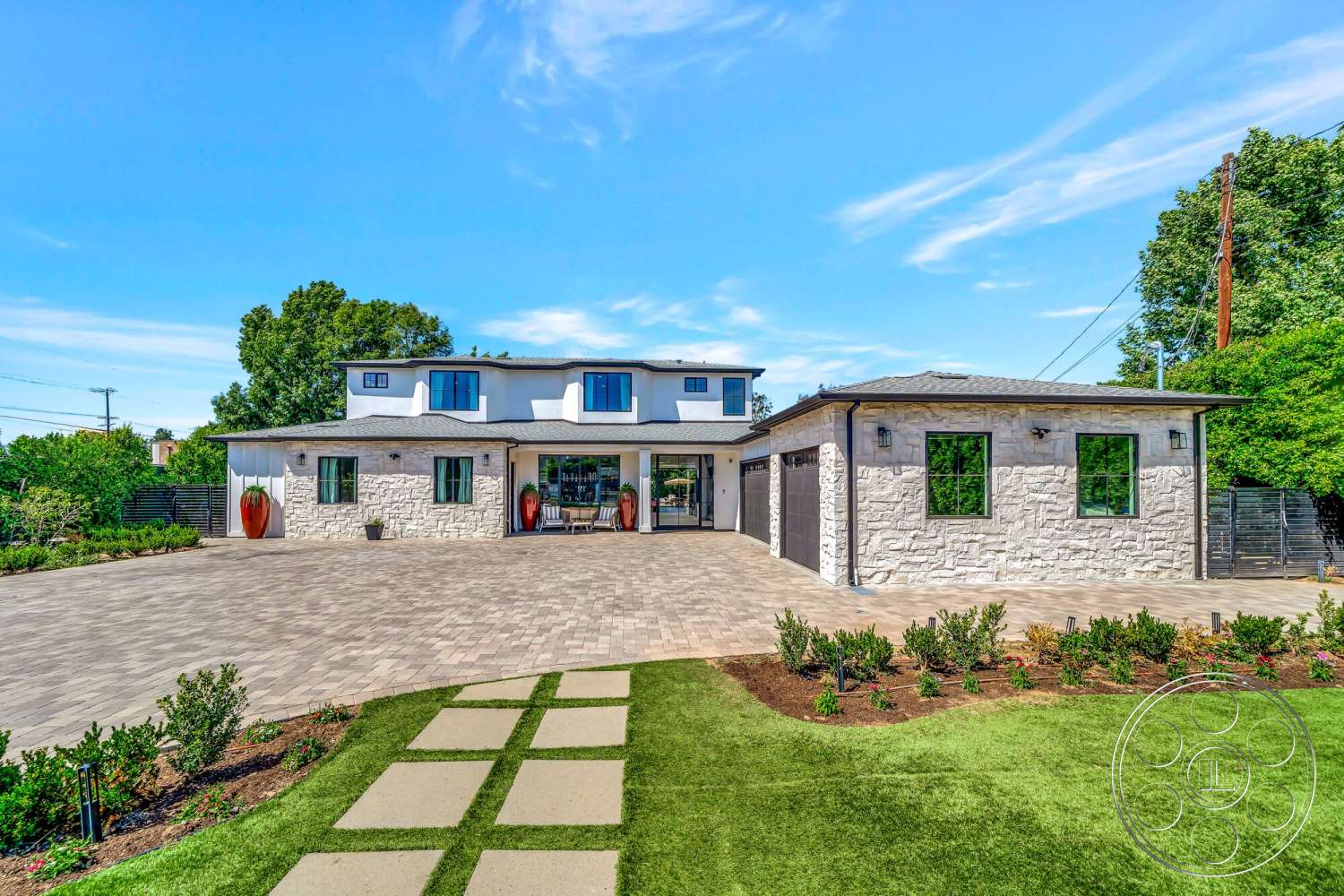 Modern 534 - large windows, exterior, paver driveway, green lawn, modern architectural style, gabled roof, planter pots, wooden entry door, landscaped garden beds, flat roof overhang, stone facade walls, rectangular front patio, vegetation surrounding property