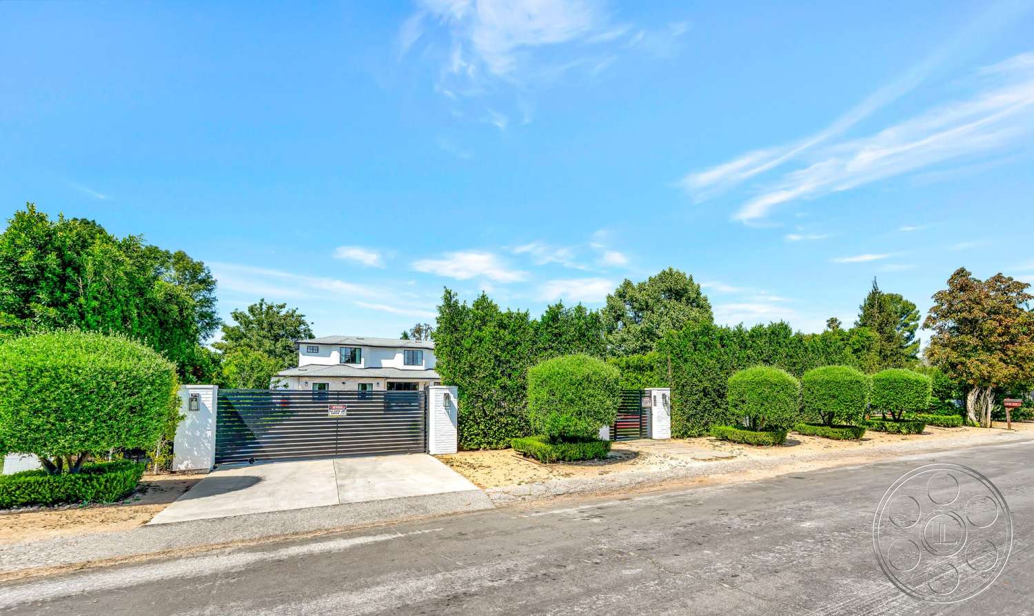 Modern 534 - exterior, suburban setting, gravel pathway, concrete driveway, curved driveway, blue sky, landscaped hedges, two-story home, green lawn area, rounded topiary shrubs, siding walls, steel sliding gate