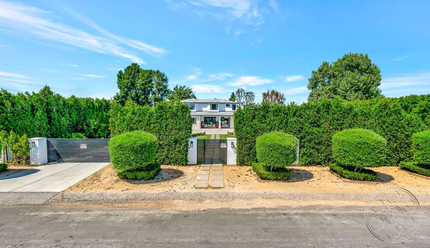 Modern 534 - large windows, exterior, lush greenery, suburban setting, landscaped front yard, stone pathway, gravel landscaping, concrete driveway, horizontal wooden fence, bright blue sky, modern two-story house, hedge perimeter, rounded topiary hedges
