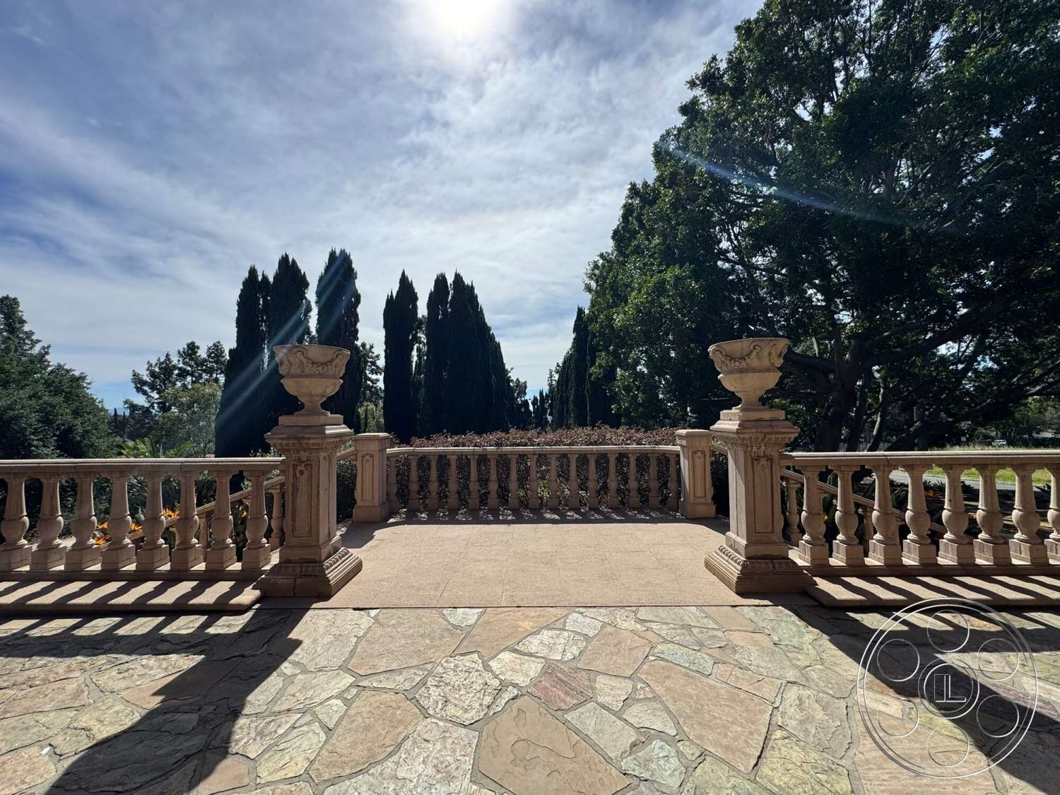 Villa Italy - exterior, tall evergreen trees, decorative stone planters, elegant architectural details, lush garden setting, sunlit outdoor space, flagstone patio flooring, ornamental stone balustrade, spacious terrace area