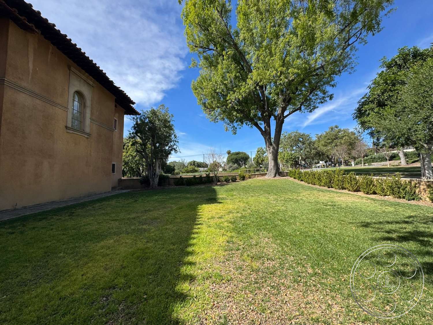 Villa Italy - exterior, paved pathway, manicured lawn, tile roof, arched windows, stucco wall finish, large shade tree, visible landscaping, low stone wall, garden hedge
