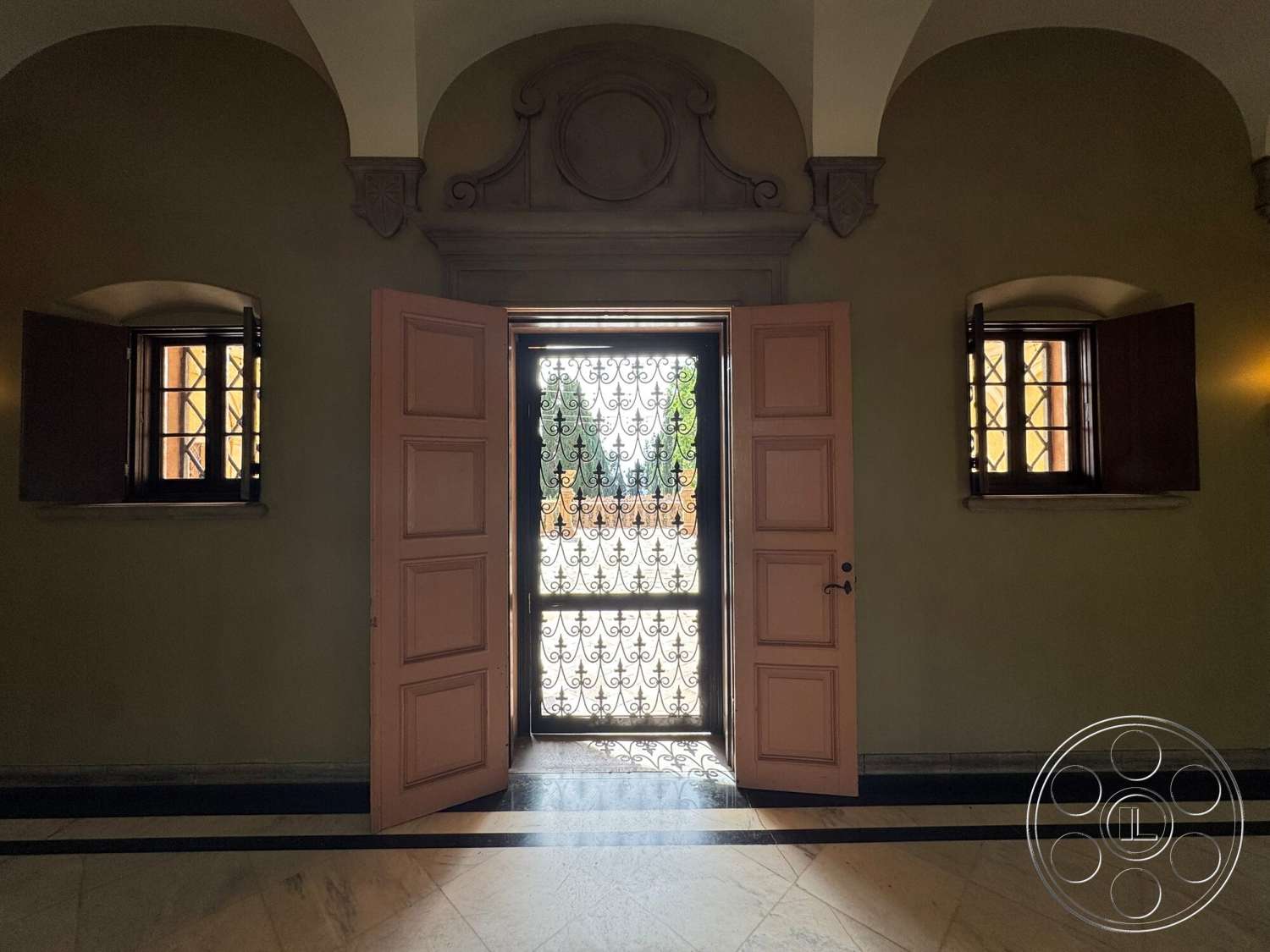 Villa Italy - arched doorways, textured plaster walls, decorative molding details, traditional window design, double wooden entry doors, wrought iron security screen door, pink painted wooden doors, marble flooring with black inlays, large open entryway