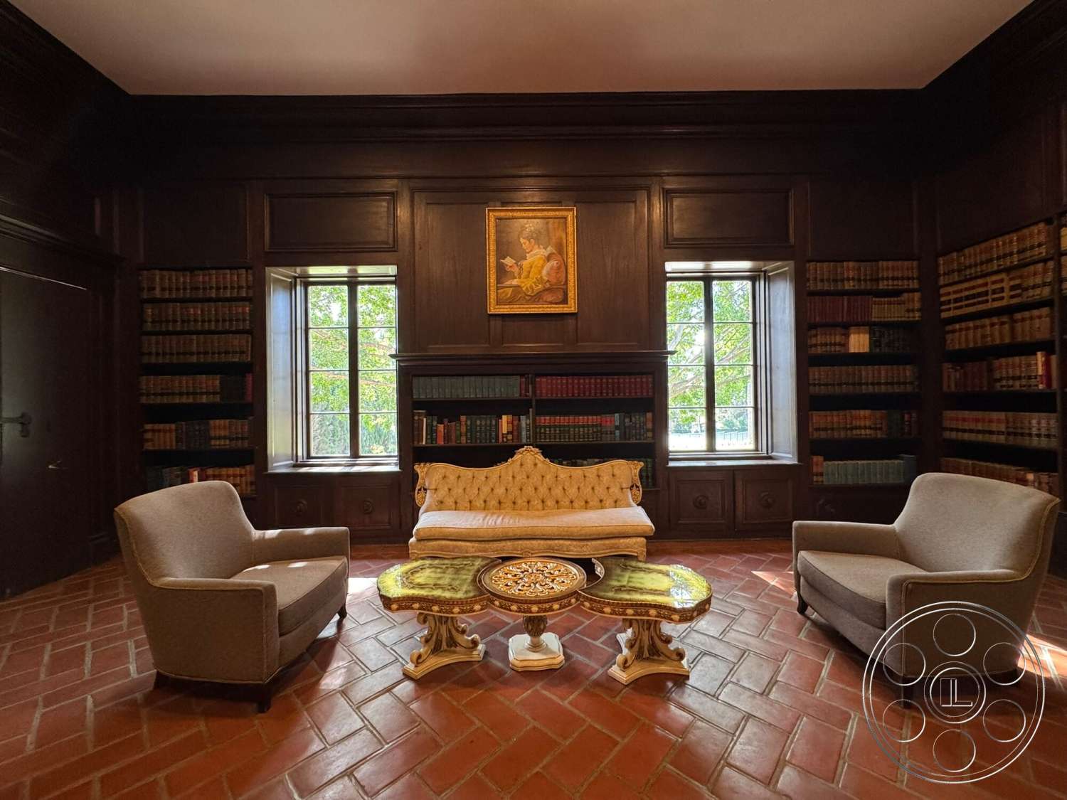 Villa Italy - brick flooring, marble coffee table, built-in bookshelves, detailed crown molding, large double-hung windows, exposed wood wall paneling, brown leather armchairs, painted portrait wall art, traditional design style