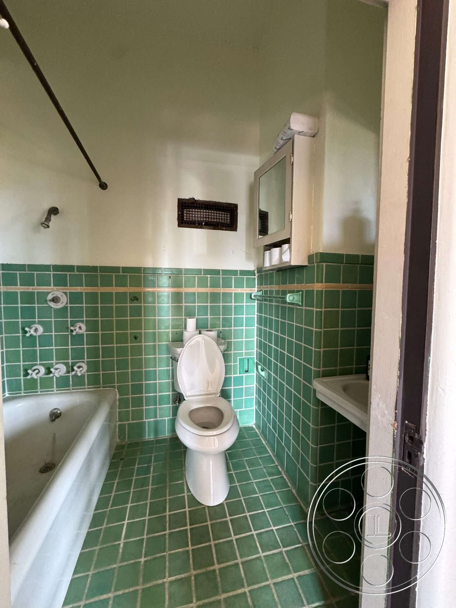 Villa Italy - white porcelain toilet, exposed plumbing, white bathtub, wall-mounted mirror, interior bathroom, chrome bathroom fixtures, glazed green tile walls, green tile floor, small window vent, built-in sink cabinet