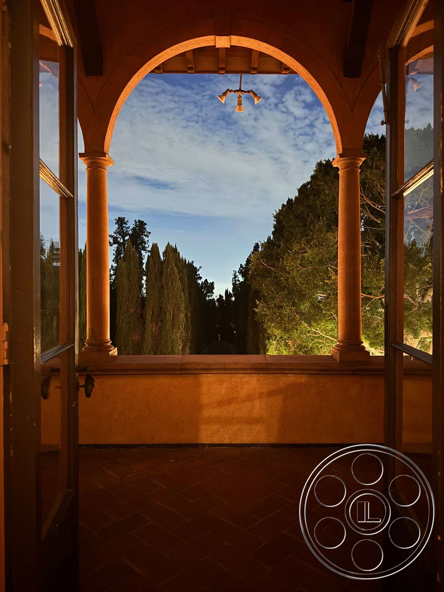 Villa Italy - exposed beam ceiling, stucco walls, arched entryway, Mediterranean architectural style, outdoor garden view, terra cotta tile flooring, interior balcony, cylinder pendant lighting, surrounding cypress trees