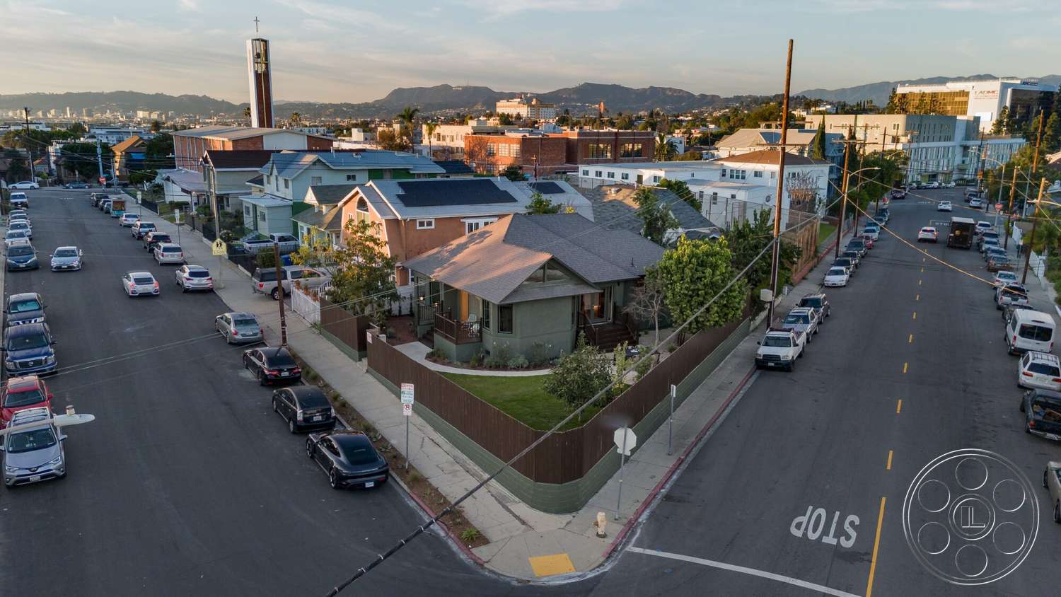 Craftsman 65 - exterior, flat roof, green siding, landscaped front yard, gabled roof, wooden fence, asphalt street, shingle roof, urban residential neighborhood, distant mountain view, craftsman-style home, driveway with parked vehicles