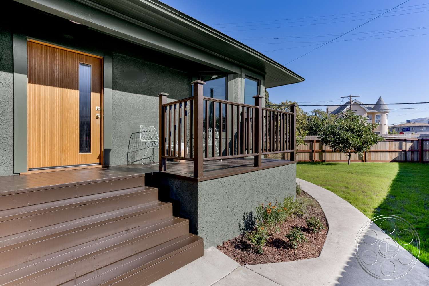 Craftsman 65 - exterior, metal railing, concrete steps, clear blue sky, green grass lawn, wooden front door, curved concrete pathway, textured stucco walls, landscaped garden bed, brown wooden decking, background fence