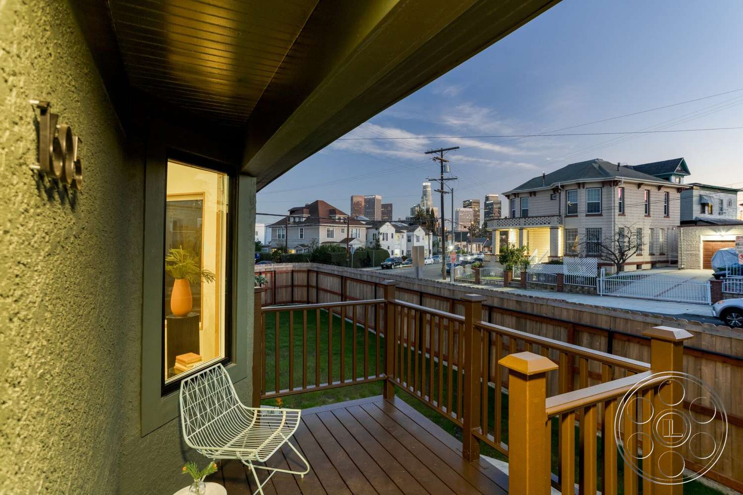 Craftsman 65 - exterior, green lawn, wood deck, city skyline view, urban residential setting, fenced backyard, textured stucco wall, painted wood railings, large window with a plant, dark trim around windows
