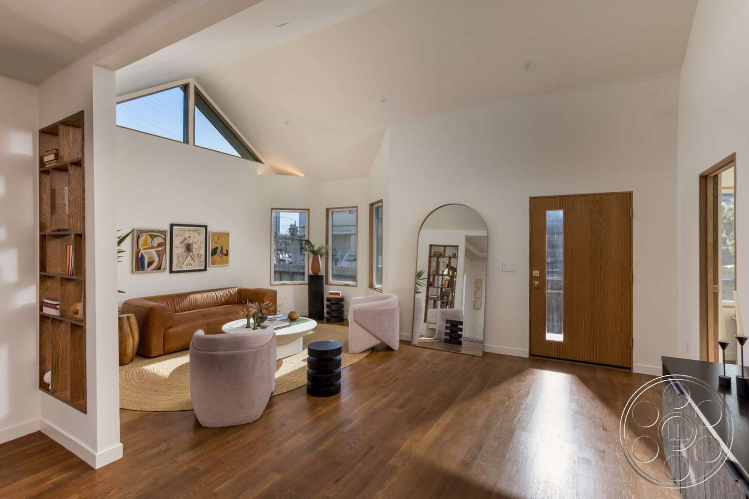Craftsman 65 - round coffee table, artwork on walls, vaulted ceiling, wooden floor, leather sofa, large floor-to-ceiling windows, indoor plant decor, arched mirror, wood paneling accent wall, modern accent chairs, natural hardwood flooring, angular ceiling shape, modern entry door, bookshelf with open shelves