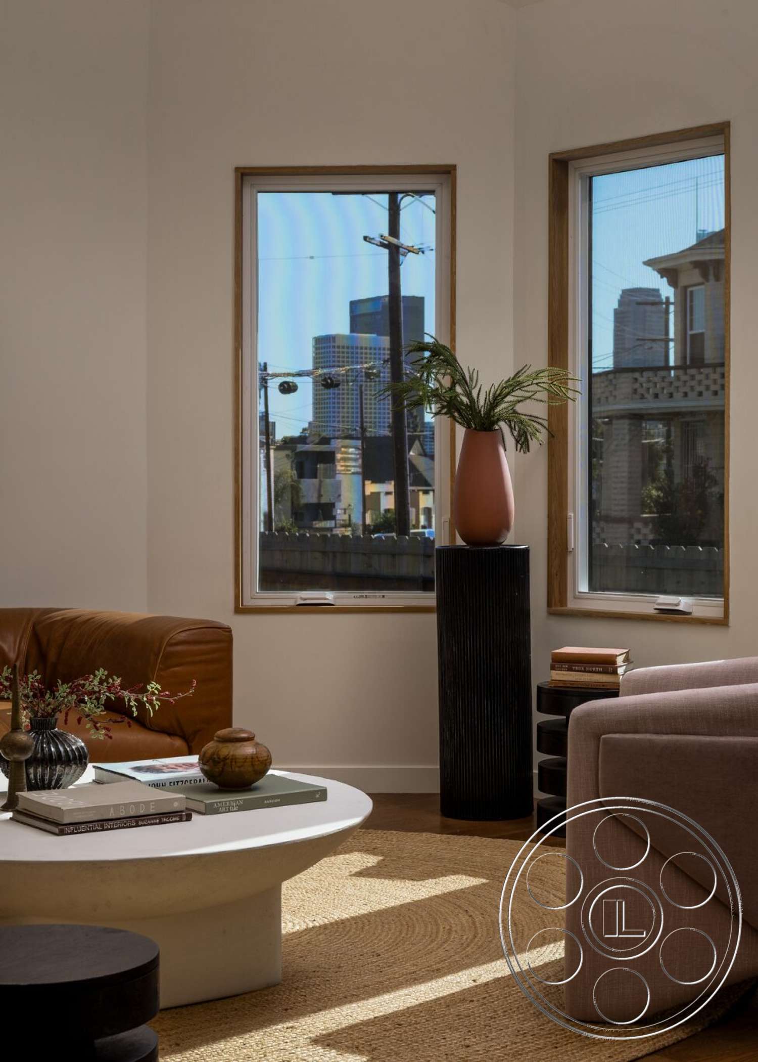 Craftsman 65 - natural light, textured area rug, open concept layout, floor-to-ceiling windows, neutral wall color, green potted plant, brown leather sofa, modern minimalist style, urban setting view, light wood window frames, white round coffee table, black cylindrical side table, ceramic decorative vase, stack of design books, soft pink upholstery