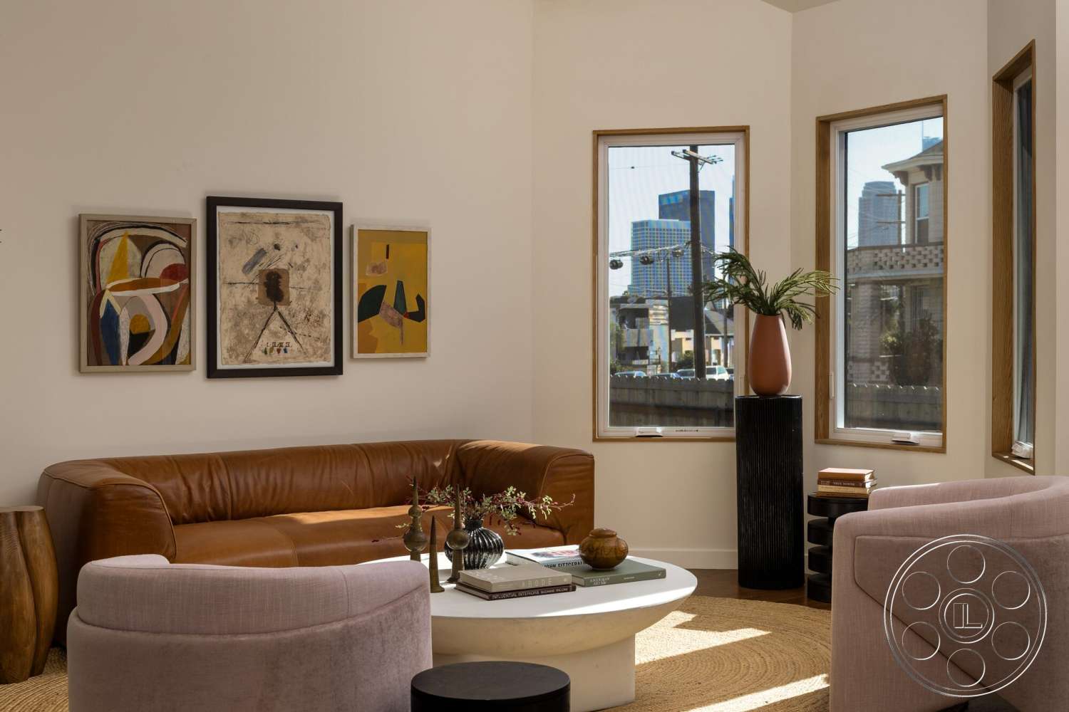 Craftsman 65 - round coffee table, artwork on wall, painted white walls, wooden side table, large floor-to-ceiling windows, leather sectional sofa, textured beige area rug, contemporary architectural style, modern home decor, exposed natural wood window trim, decorative plant in ceramic vase, soft pink accent chairs, suburban living room setting