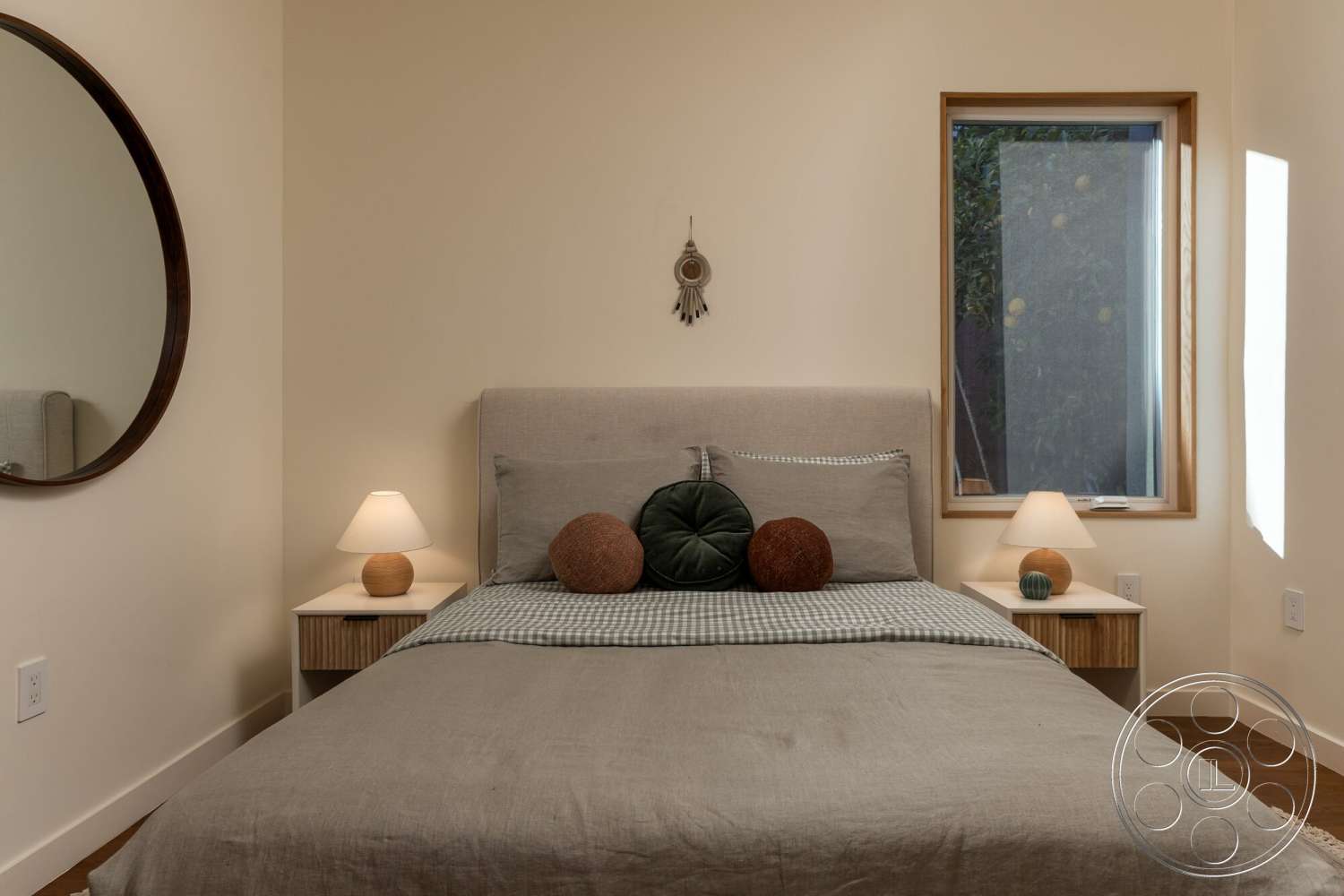 Craftsman 65 - neutral color palette, textured bedding, wooden nightstands, smooth white painted walls, minimalist wall decor, round wall mirror, plaid decorative pillows, large window with wooden frame, upholstered bed frame, softwood bedroom floors, modern pendant lamps