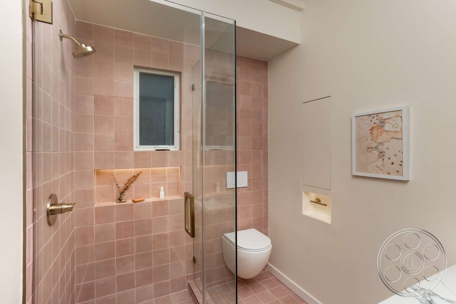 Craftsman 65 - tile flooring, glass shower enclosure, neutral wall color, white toilet, framed artwork on wall, brass shower fixtures, pink tile shower walls, recessed niche shelf with lighting