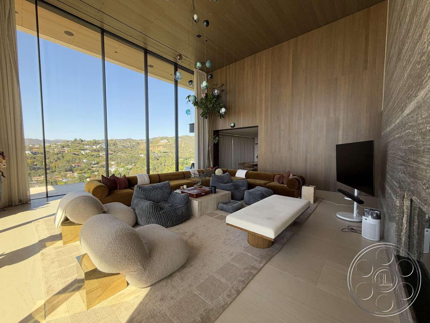 CK Mansion - textured area rug, open-concept living space, contemporary coffee table, floor-to-ceiling glass windows, natural light-filled room, exposed wood paneling walls, suspended pendant lights, light-colored ceramic tile flooring, minimalist entertainment unit, large sectional sofa with velvet upholstery, modern recessed ceiling lights, landscape view through glass, high ceiling with wood slats