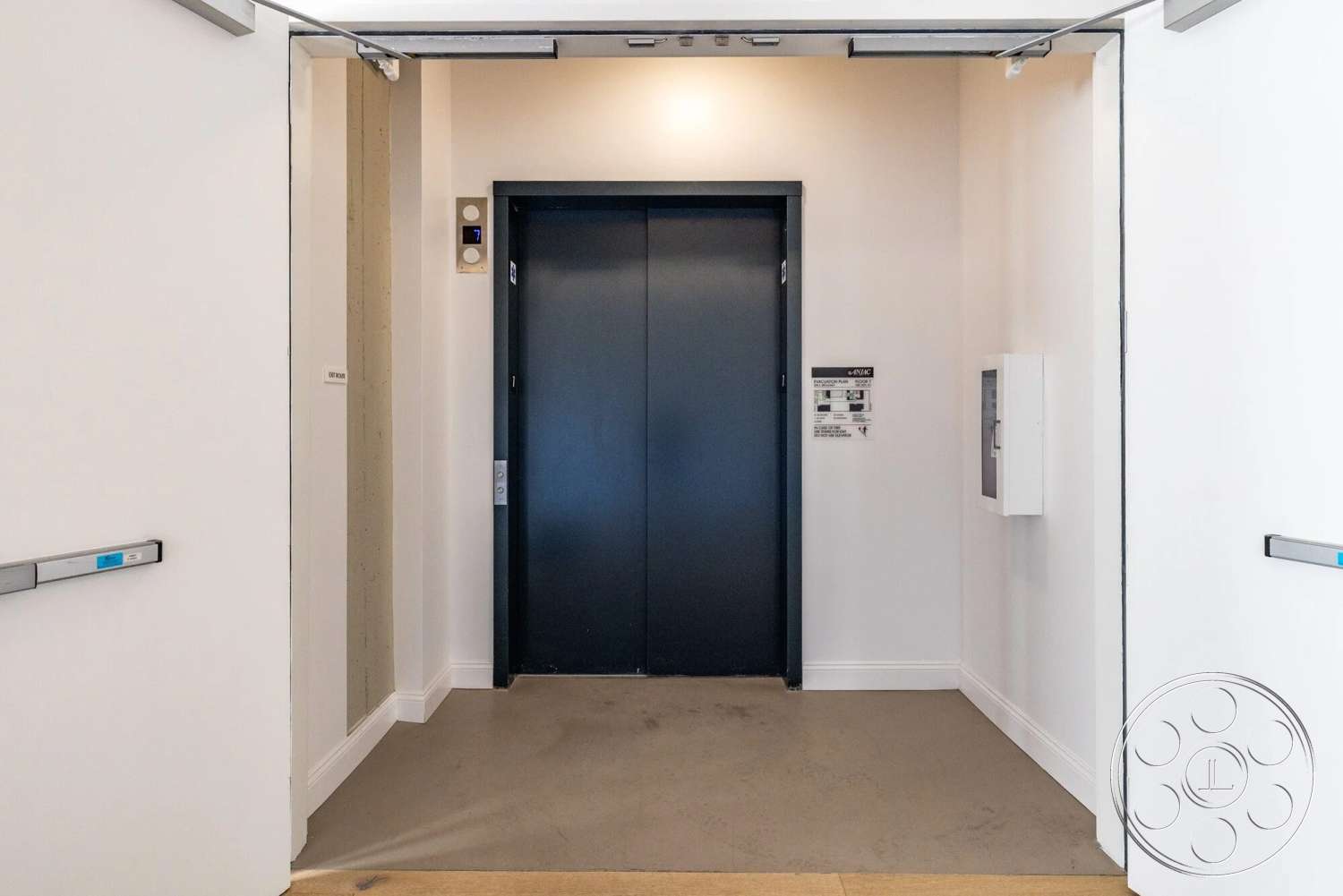 Loft 1 - modern architecture, minimalist design, concrete flooring, lighting fixtures, white painted walls, interior elevator space, black elevator doors, modern wall paneling, door access control panel