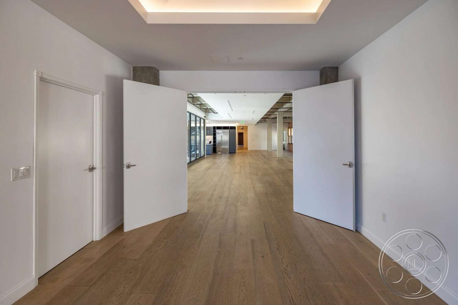 Loft 1 - hardwood flooring, minimalist design, open floor plan, exposed ceiling structure, contemporary interior design, glass partition walls, white painted walls, ambient ceiling lighting, modern double doors