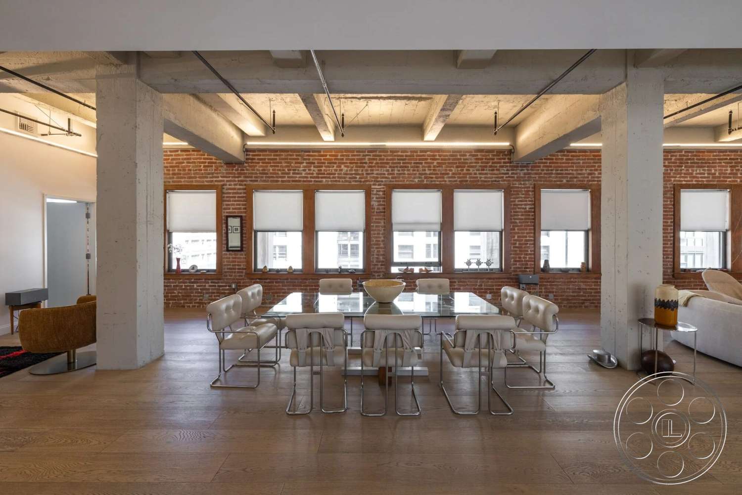 Loft 1 - hardwood flooring, upholstered dining chairs, urban setting, floor-to-ceiling windows, neutral color scheme, contemporary living room, modern glass dining table, open floor plan interior, exposed brick accent wall, concrete support columns, metal chair frames, industrial-style ceiling beams