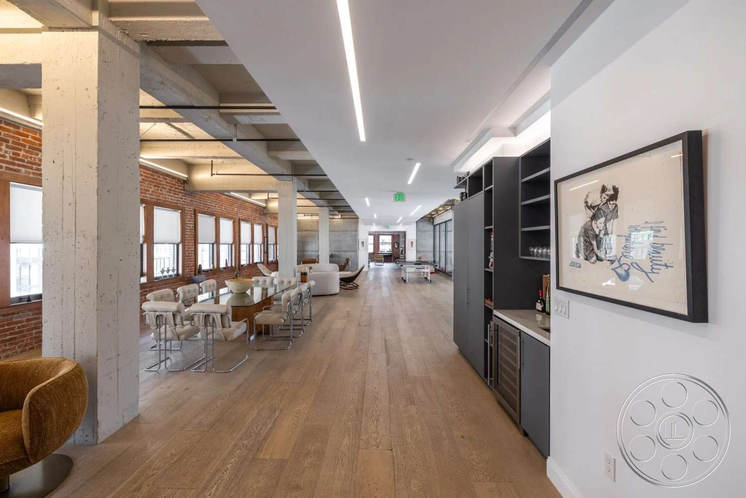 Loft 1 - neutral color palette, hardwood flooring, recessed lighting, open floor plan, glass windows, modern dining area, exposed brick accent wall, concrete support columns, minimalist kitchen cabinetry, industrial style ceiling beams, comfortable lounge seating, art framed on wall