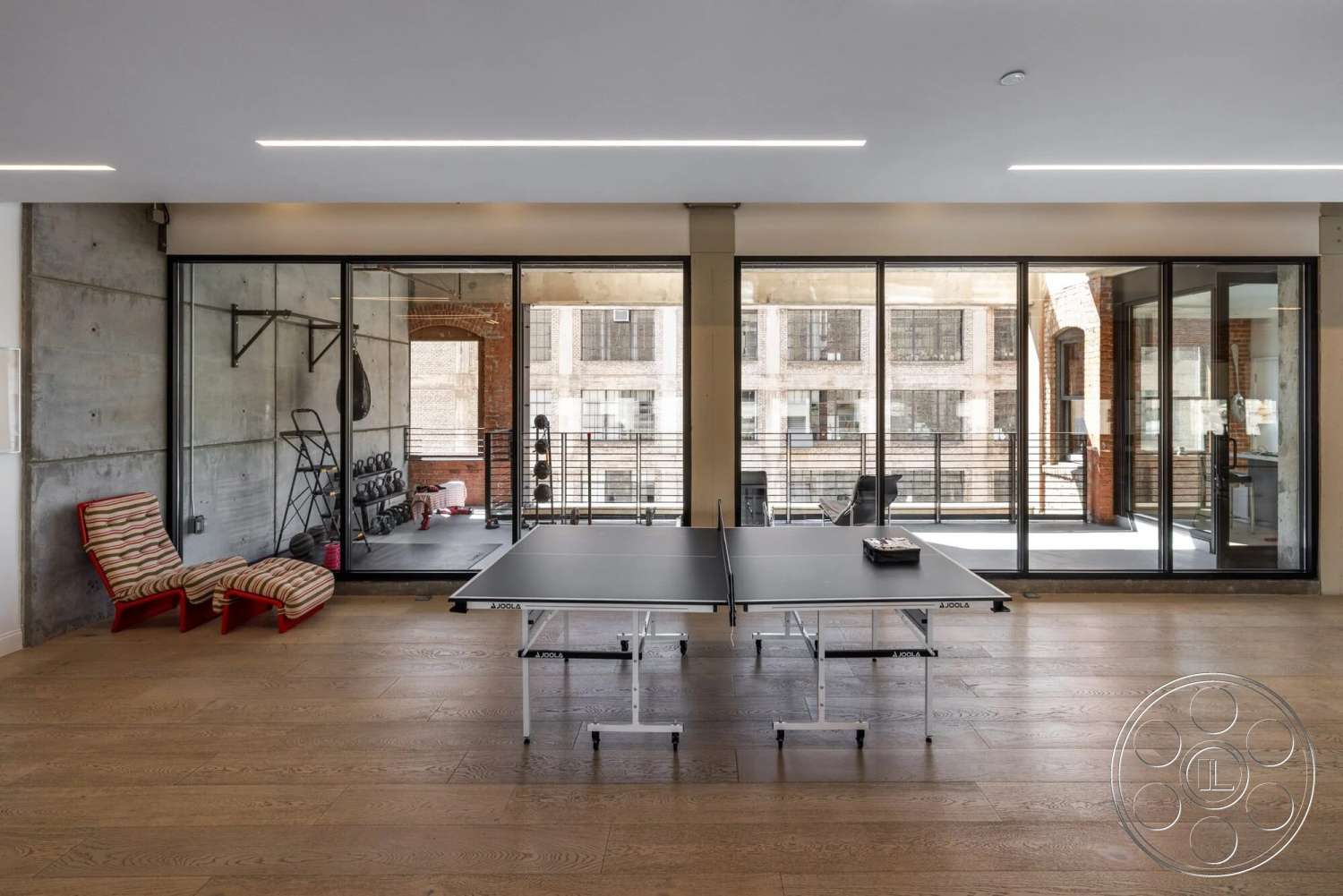 Loft 1 - hardwood flooring, open floor plan, modern lighting fixtures, exposed brick wall, steel railing, fitness area, ping pong table, glass partition walls, concrete accent wall