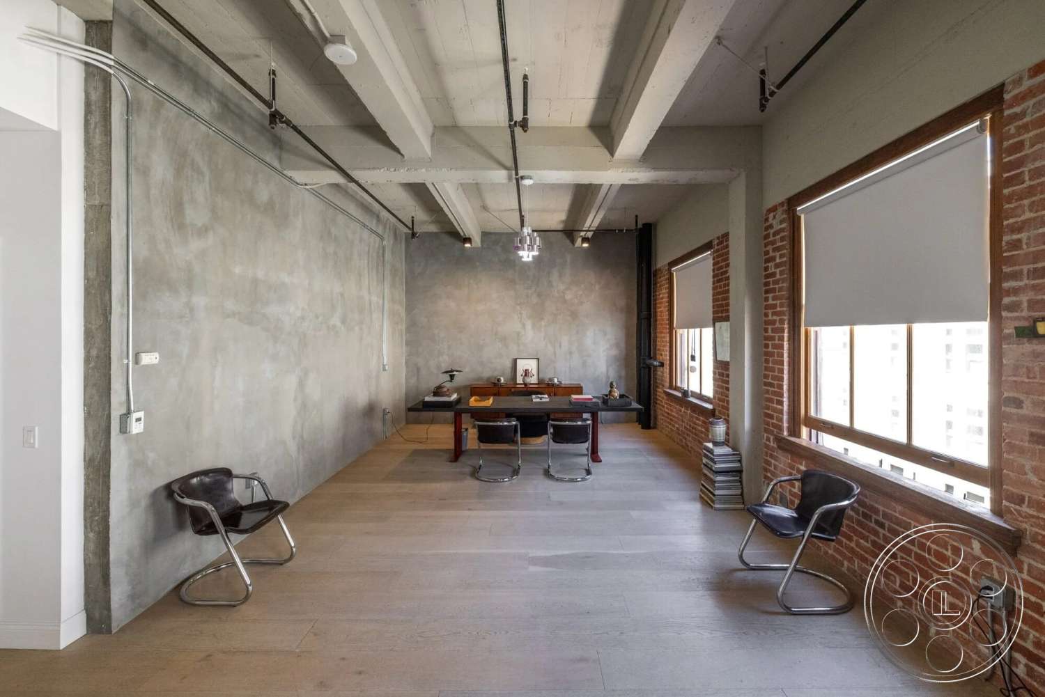 Loft 1 - neutral color palette, hardwood flooring, modern pendant lighting, smooth concrete wall, minimalist furniture design, exposed brick accent wall, open workspace layout, urban office interior, large windows with wooden frames, industrial ceiling beams