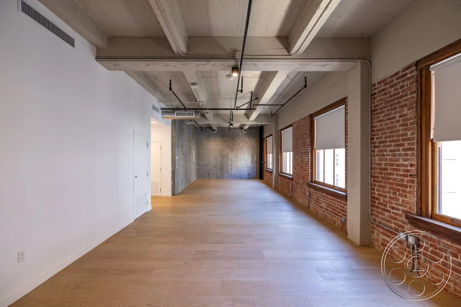Loft 1 - minimalist aesthetic, light wood flooring, exposed brick walls, painted white walls, industrial-style interior, concrete ceiling beams, modern open floor plan, large windows with wood trim