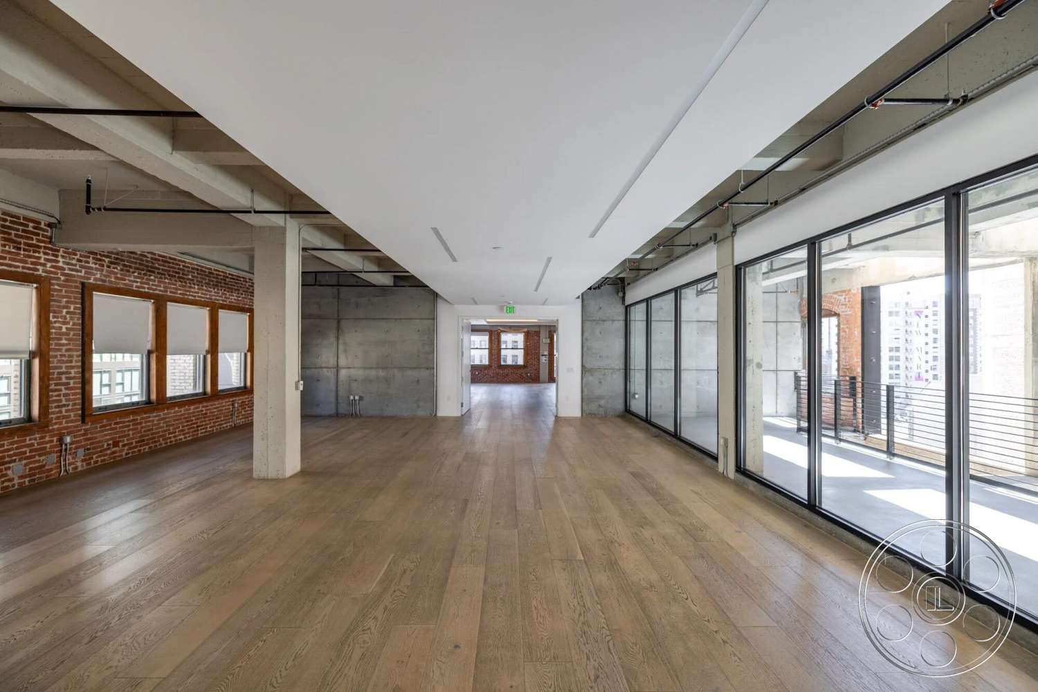Loft 1 - hardwood flooring, open concept layout, concrete walls, industrial style, floor-to-ceiling windows, steel railing, exposed brick accent wall, large urban loft
