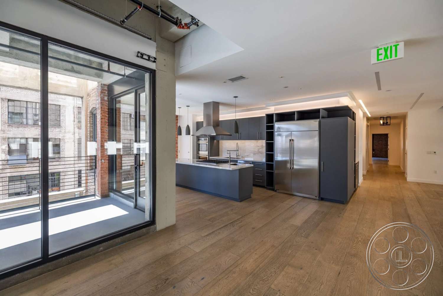 Loft 1 - neutral color palette, modern pendant lighting, exposed concrete walls, urban setting, floor-to-ceiling windows, spacious hallway, contemporary interior design, stainless steel kitchen appliances, hardwood kitchen flooring, marble kitchen backsplash, exterior glass balcony railing, kitchen island with seating, industrial-style loft, open-plan kitchen and living area, gray kitchen cabinetry, polished concrete ceiling, architectural details featuring clean lines
