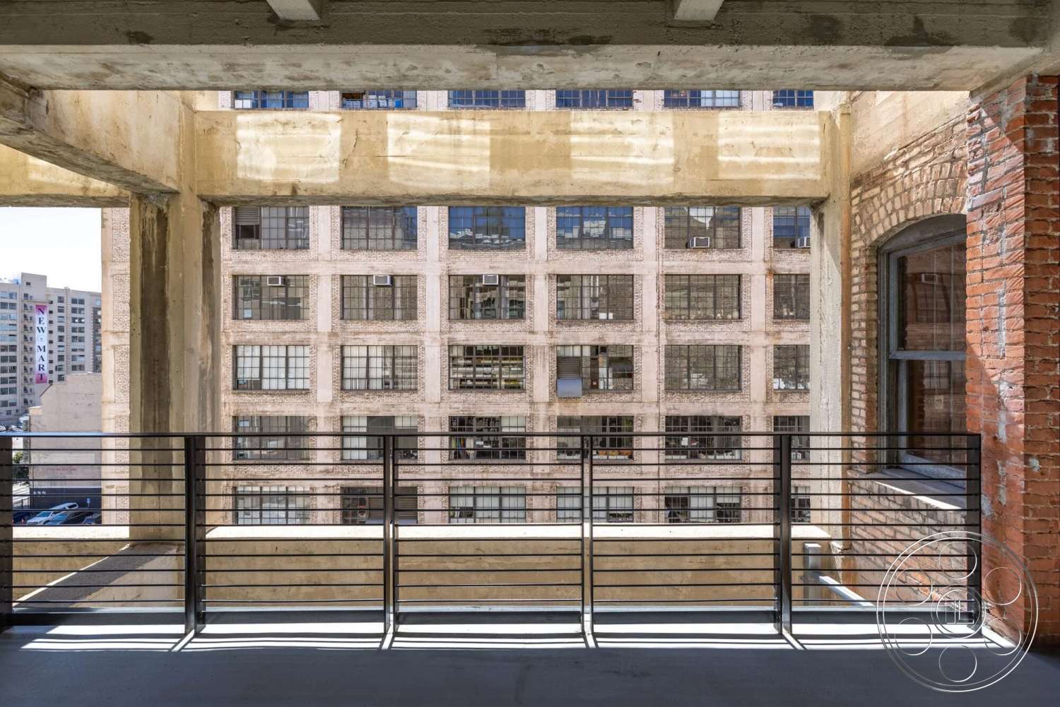 Loft 1 - polished concrete flooring, exposed brick walls, large industrial windows, metal railing balcony, urban loft setting, exposed concrete beams