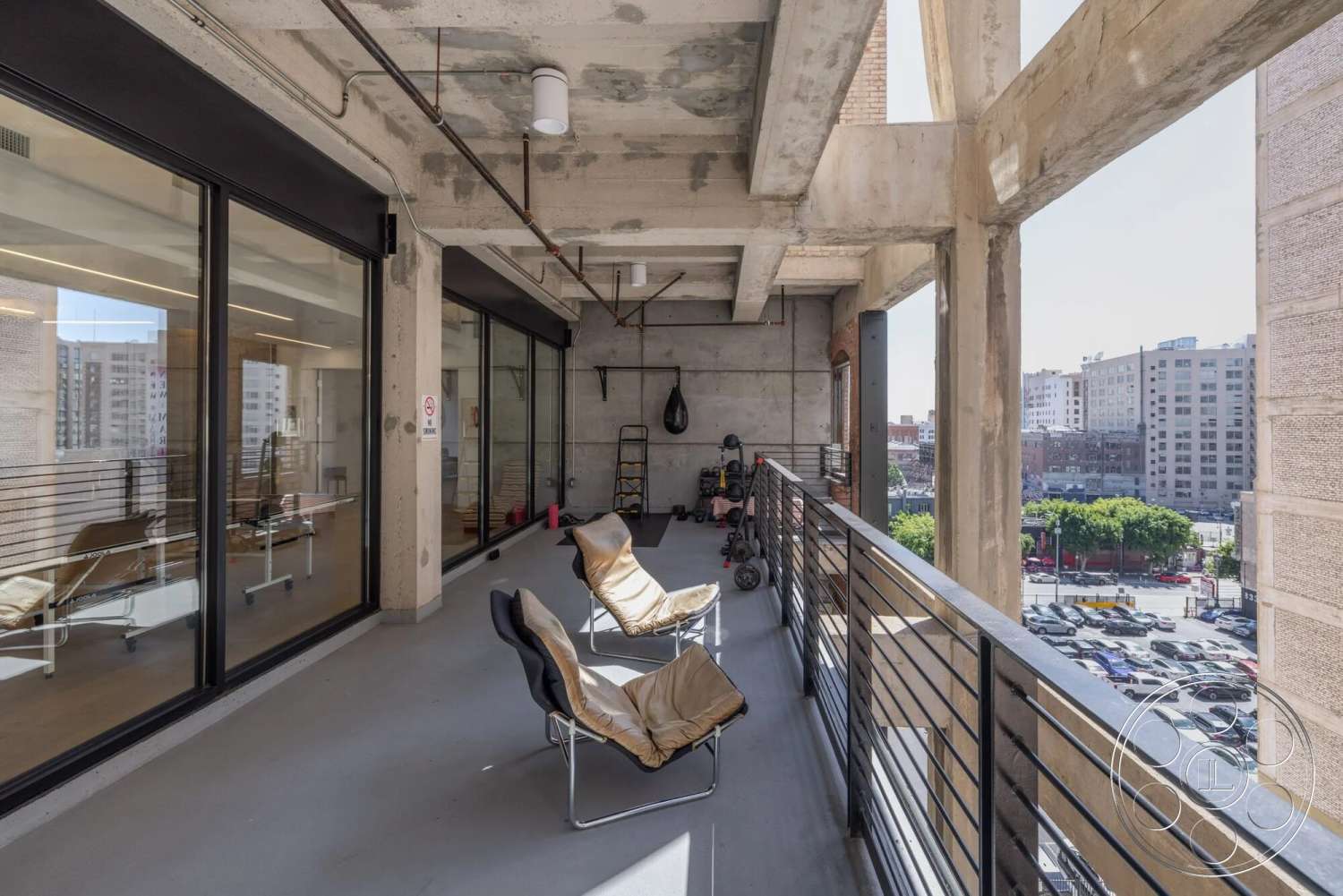 Loft 1 - exterior, minimalist design elements, glass sliding doors, urban skyline view, large floor-to-ceiling windows, exposed concrete ceiling, industrial architectural style, concrete balcony floor, steel balcony railing, open-air fitness area
