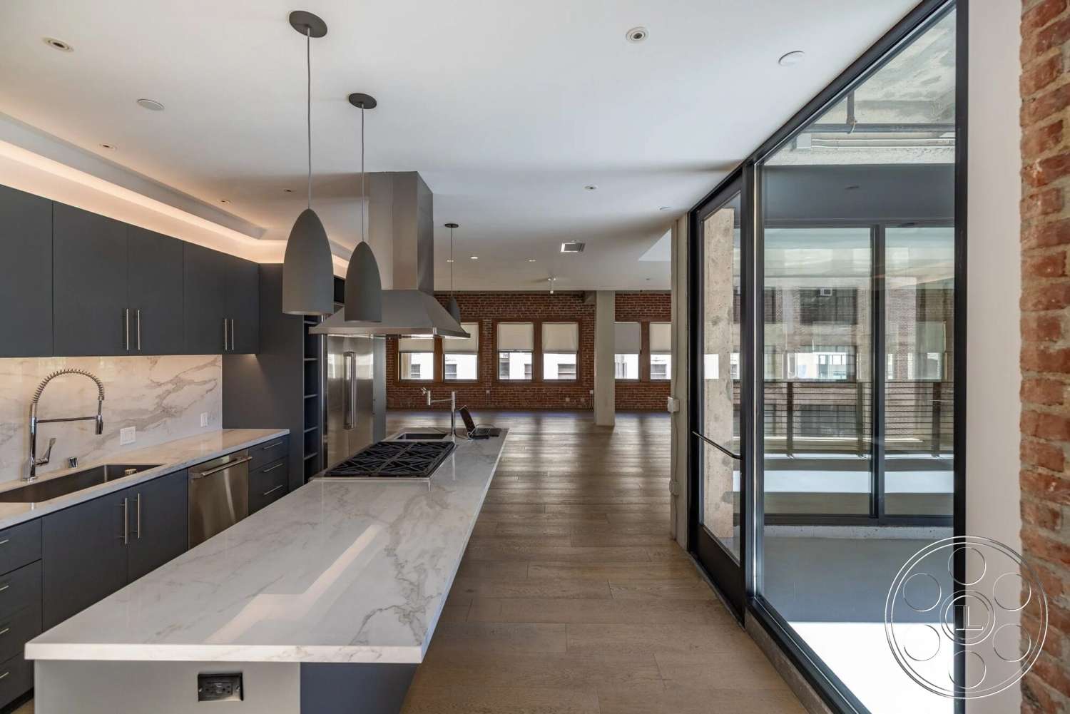 Loft 1 - modern kitchen, hardwood flooring, contemporary design, open floor plan, stainless steel appliances, dark cabinetry, floor-to-ceiling windows, marble countertop, pendant lighting fixtures, exposed brick accent wall, industrial-style details