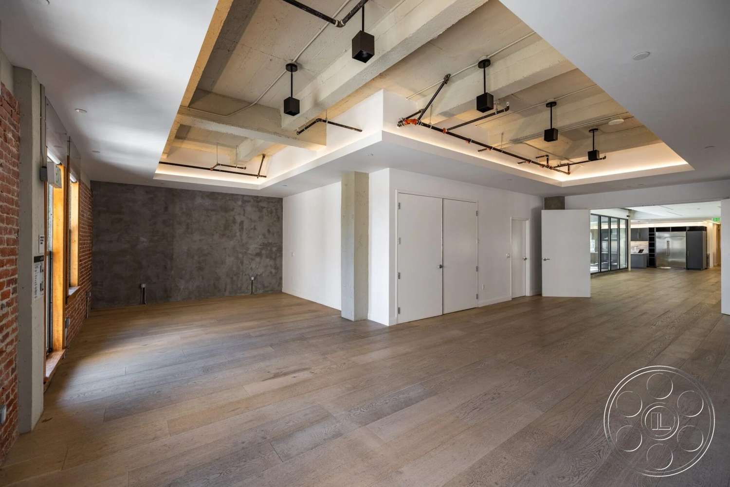 Loft 1 - neutral color palette, open floor plan, modern interior, floor-to-ceiling windows, concrete ceiling, smooth wall finish, exposed brick accent wall, track lighting fixtures, industrial style architecture, wood plank flooring
