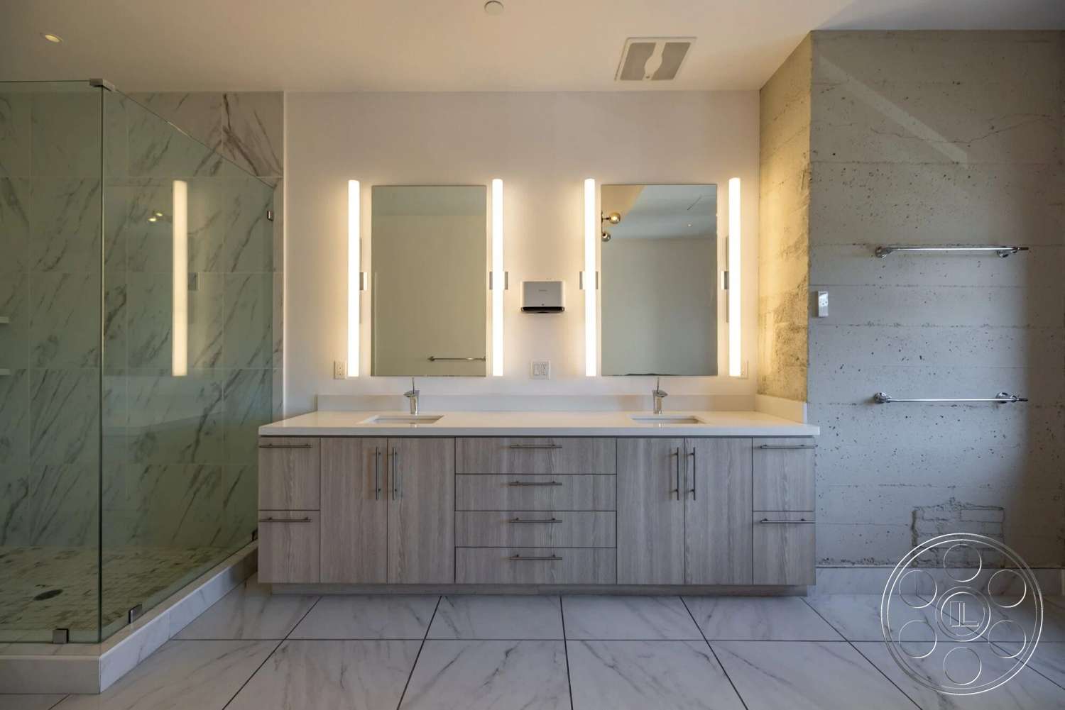 Loft 1 - floating shelves, frameless glass shower enclosure, marble bathroom flooring, linear recessed lighting, modern wooden bathroom vanity with drawers, quartz countertop with undermount sink, textured concrete feature wall, backlit wall-mounted vanity mirrors, porcelain wall tiles with marble pattern, chrome towel bars