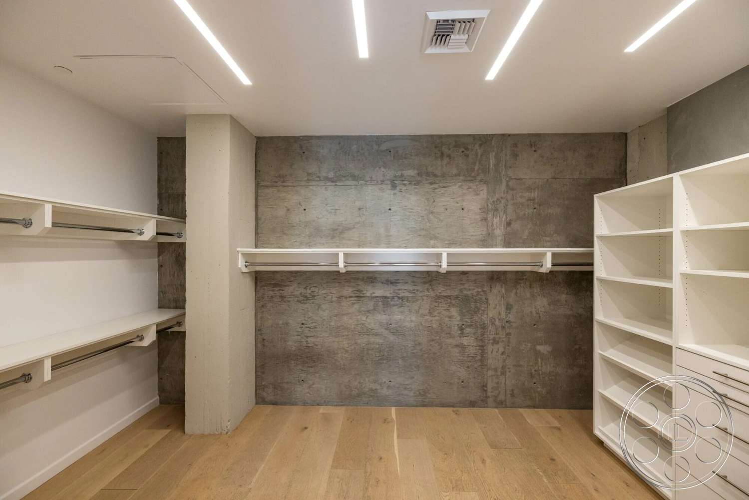Loft 1 - wood flooring, minimalist design, concrete walls, exposed ceiling, linear ceiling lights, open closet space, modern storage solutions, white painted shelving