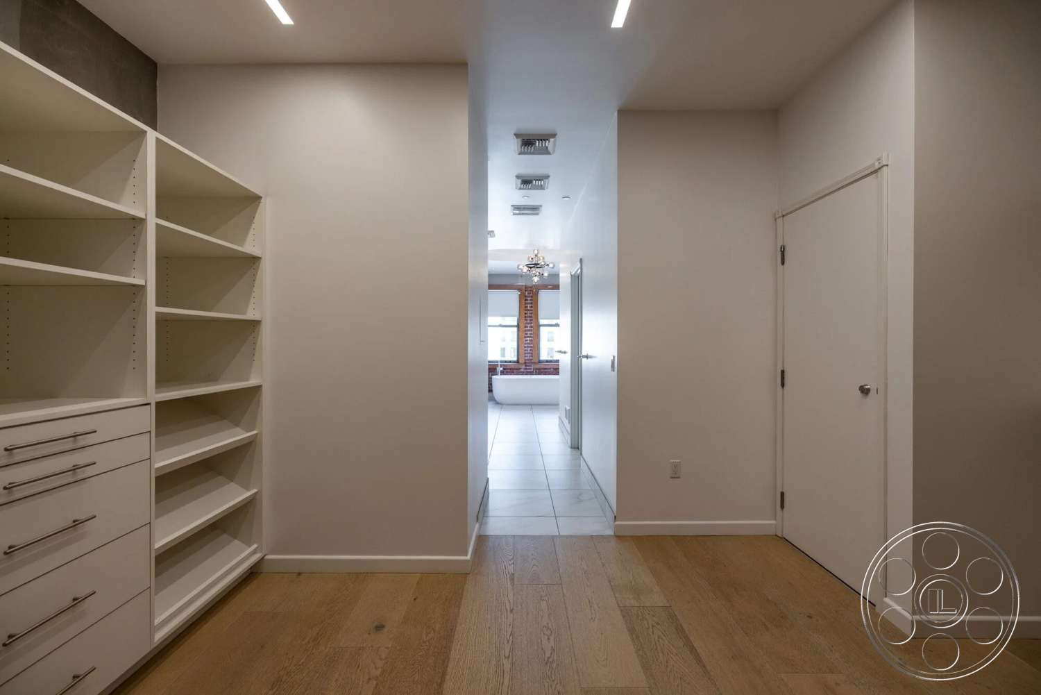 Loft 1 - minimalist design, hardwood hallway floors, white painted walls, modern architectural details, built-in white shelving units, tile flooring in the background, light fixture chandelier