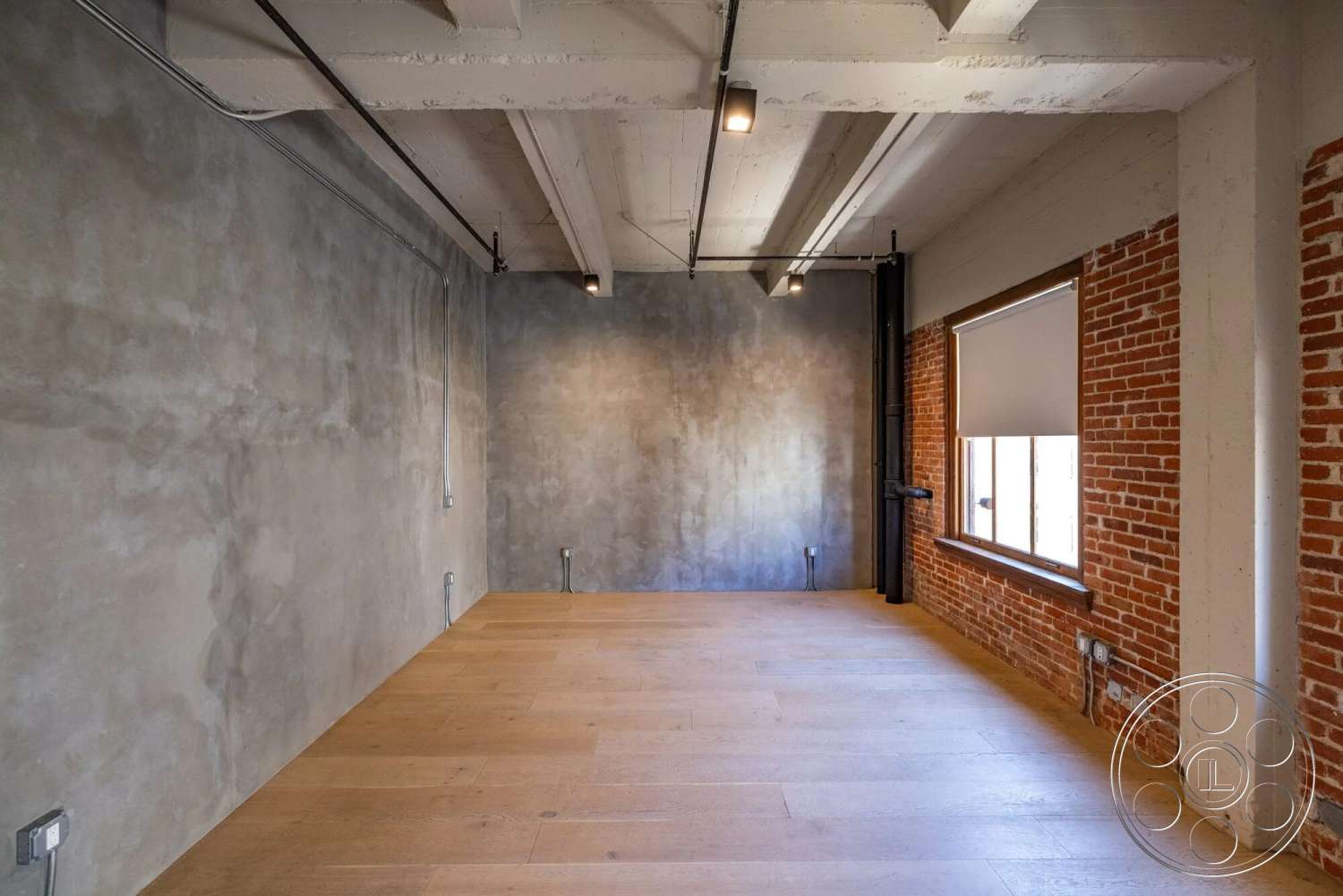 Loft 1 - neutral color palette, open floor plan, concrete walls, industrial lighting fixtures, exposed wood ceiling beams, exposed brick accent wall, wood plank flooring