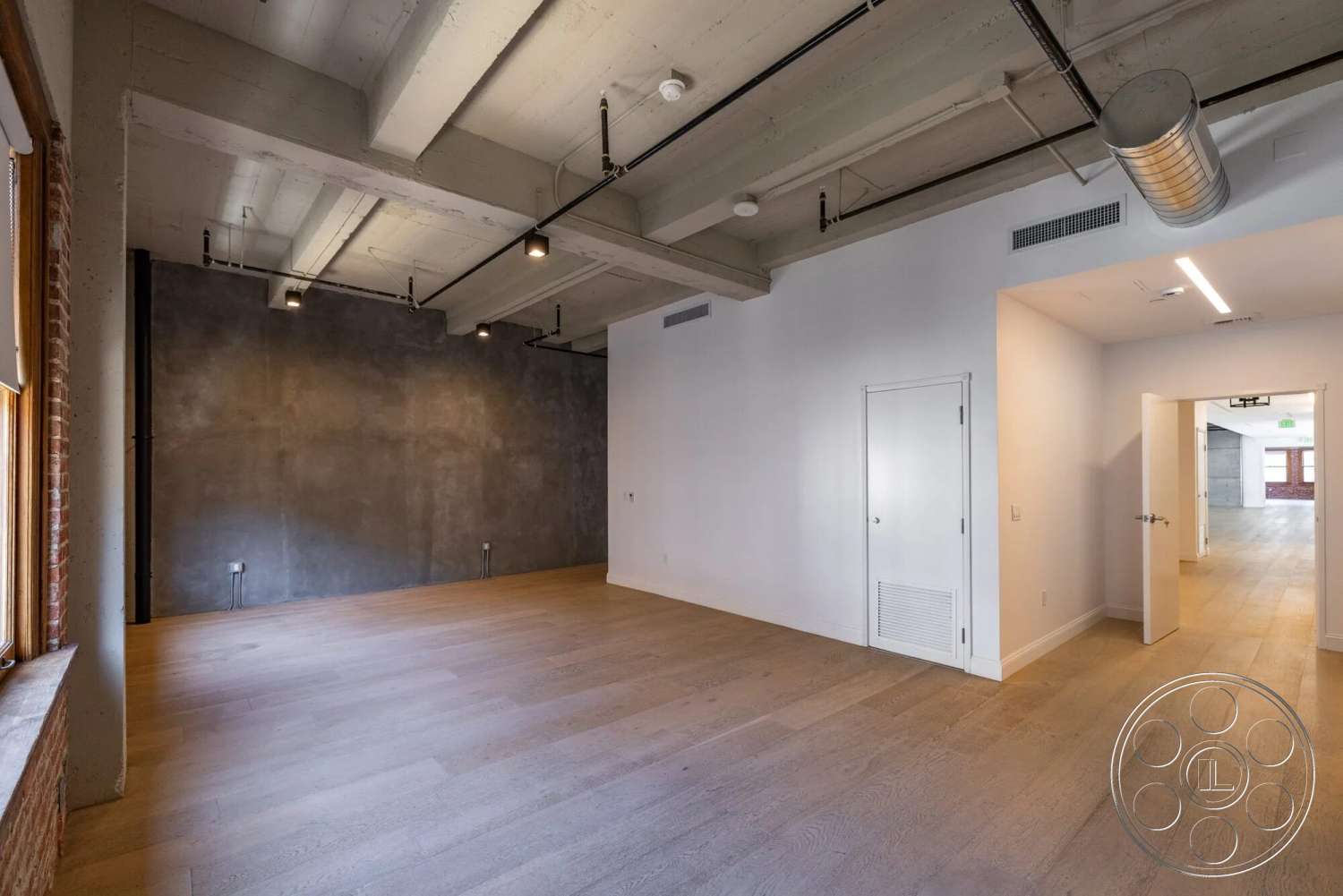 Loft 1 - large windows, minimalist design, open floor plan, exposed brick wall, exposed concrete ceiling, textured plaster wall, industrial-style lighting fixtures, polished hardwood flooring, interior room