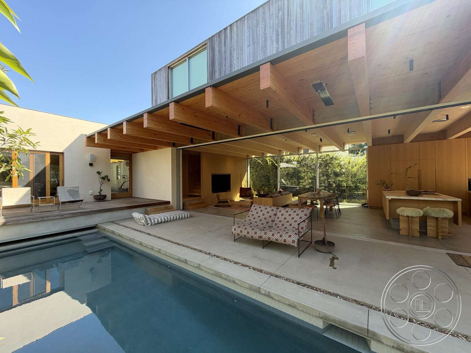 Retro House - exterior, minimalist design, stainless steel appliances, glass sliding doors, floor-to-ceiling windows, textured plaster walls, concrete pool deck, rectangular pool, wood ceiling beams, modern dining area, urban dwelling, light wood accent wall, open-concept living area, wood deck flooring, sunlit outdoor space, built-in wood cabinets, modern patio lounge furniture, natural greenery landscaping