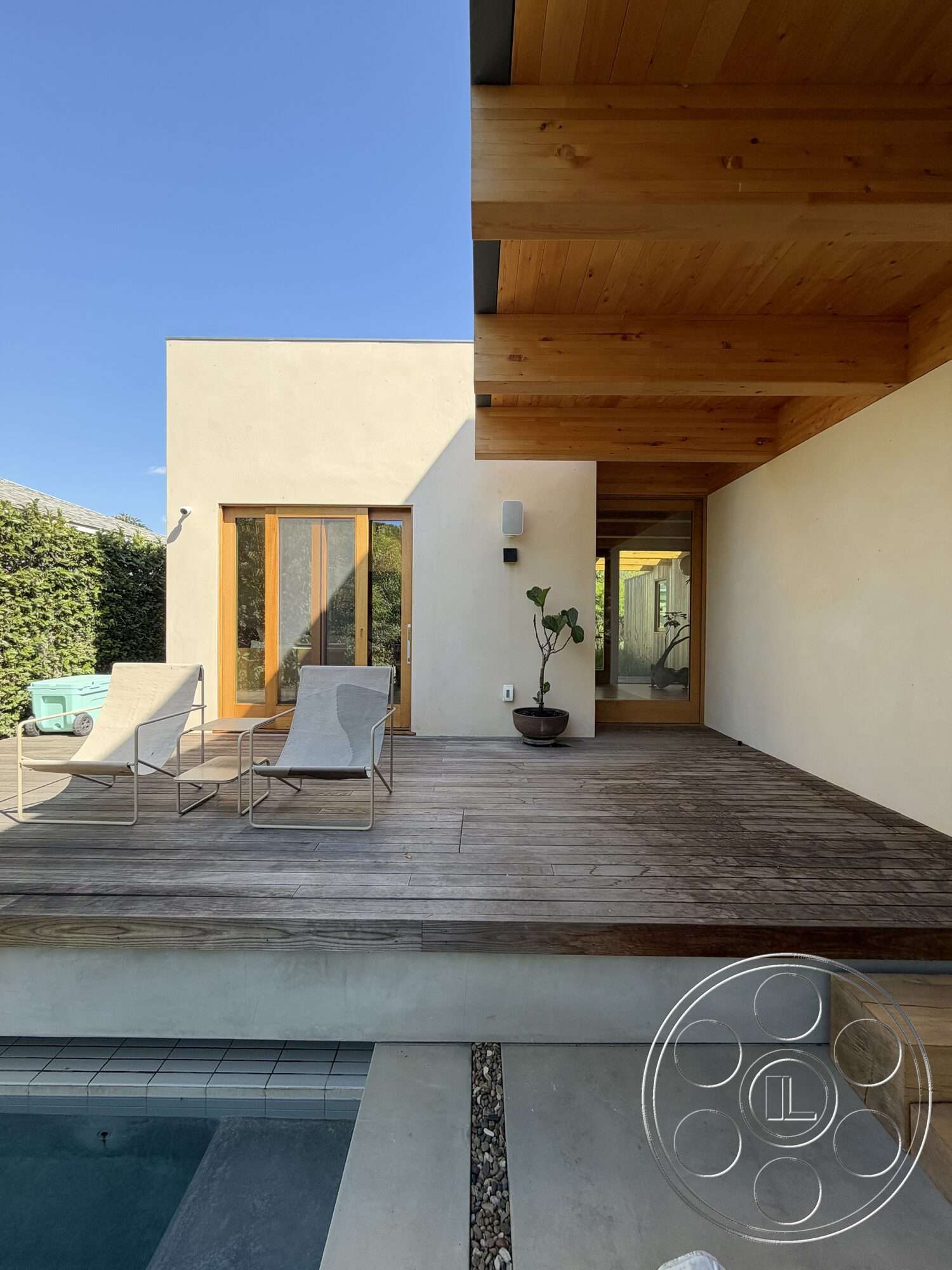 Retro House - exterior, minimalist design, natural wood accents, outdoor seating area, landscaped greenery, rectangular swimming pool, floor-to-ceiling windows, modern architectural style, stucco walls, wood beam ceiling, concrete pool border, wooden deck floor