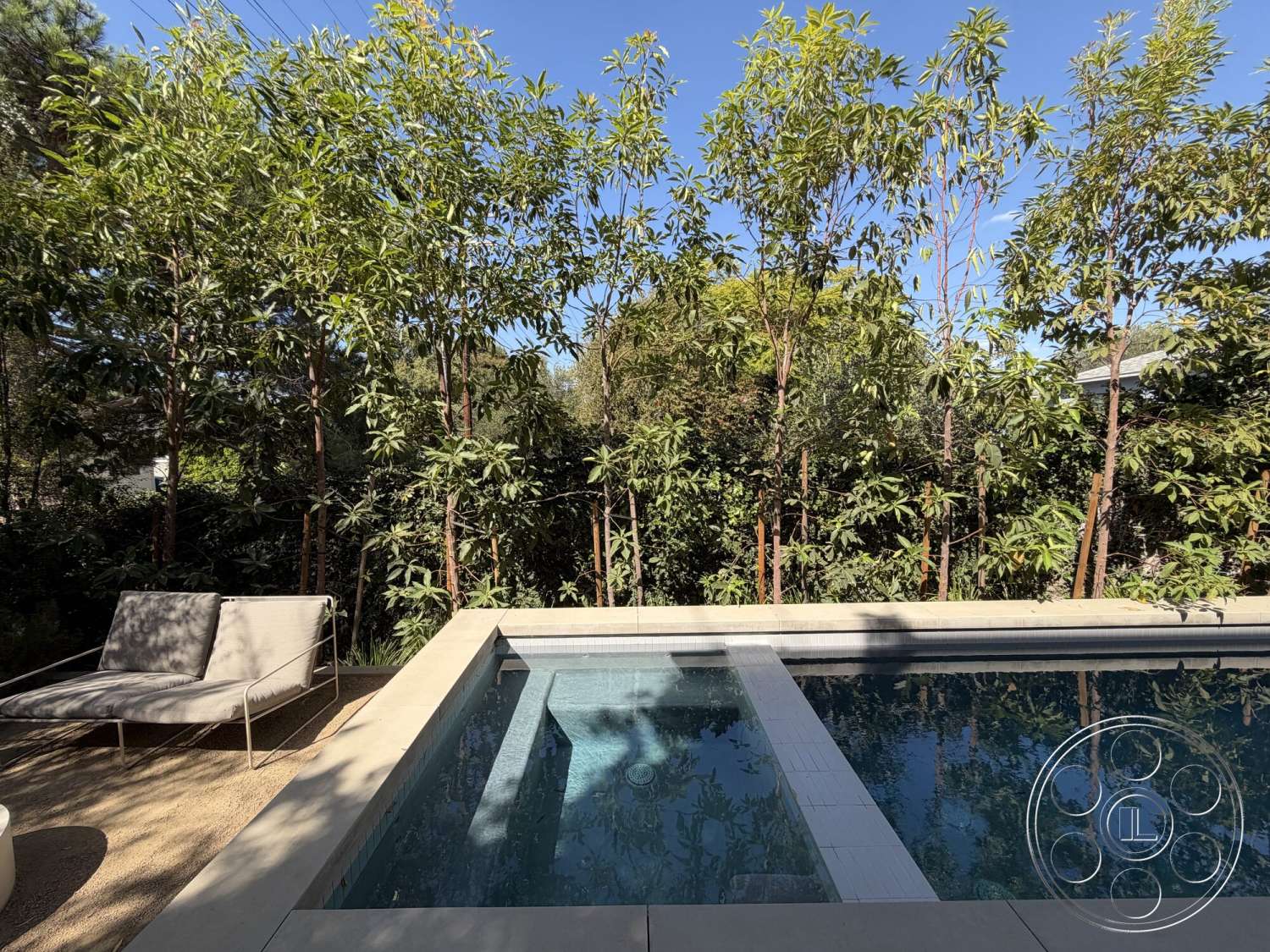 Retro House - exterior, sun loungers, infinity pool, modern outdoor space, stone patio flooring, concrete pool border, landscaped garden with trees, tile pool decking, tranquil backyard setting
