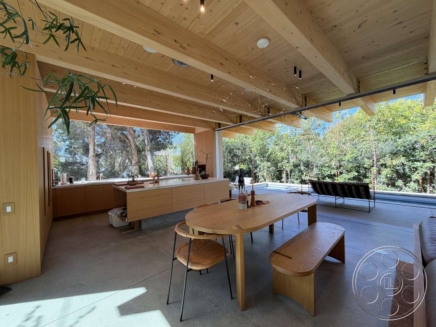 Retro House - minimalist aesthetic, concrete flooring, wood dining table, floor-to-ceiling windows, outdoor view, surrounded by trees, wooden dining chairs, natural light flooding, modern kitchen design, contemporary architectural style, exposed wood ceiling beams, open concept kitchen, light wood paneling kitchen cabinets