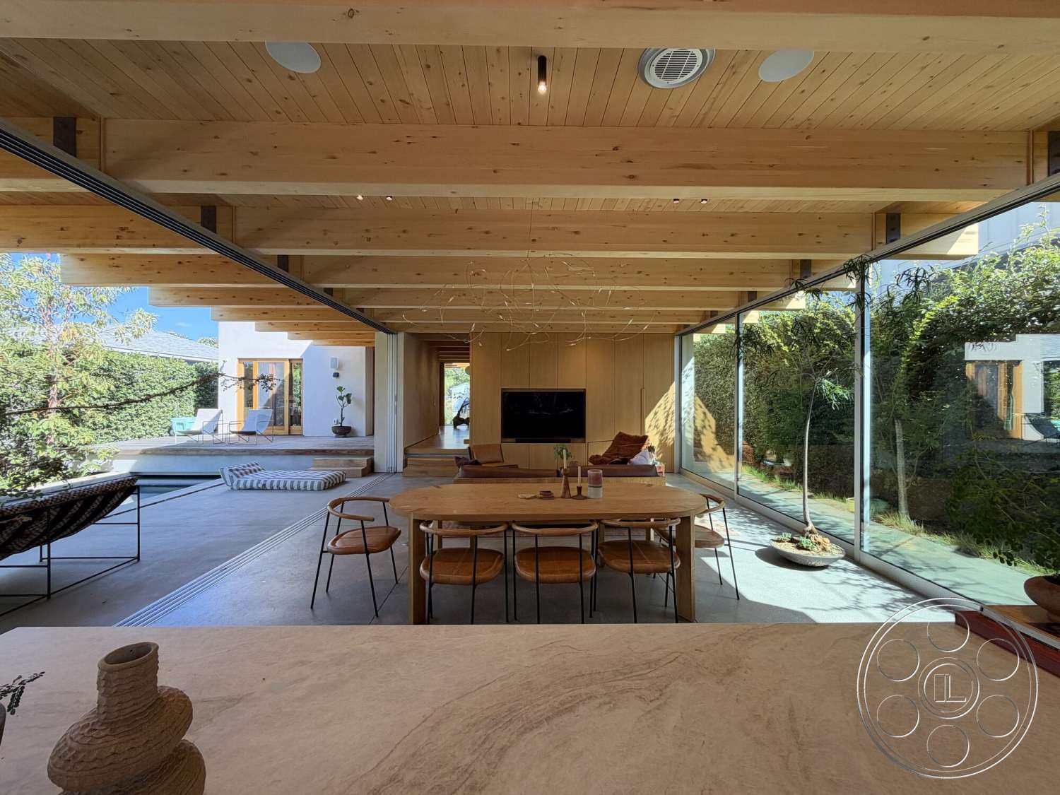 Retro House - white walls, minimalist decor, natural light, open floor plan, concrete flooring, indoor-outdoor flow, wood dining table, pool view, modern aesthetic, stone planter, exposed wood ceiling beams, landscaped patio, glass wall sections, bamboo dining chairs